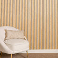 Beige chair with a decorative pillow against a oak on a light grey wall.