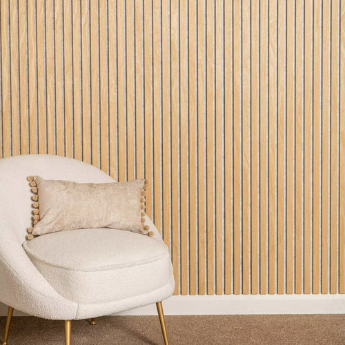 Beige chair with a decorative pillow against a oak on a light grey wall.