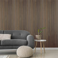 Modern living room with a gray sofa, white pouf, and small table against a walnut wooden panel wall.